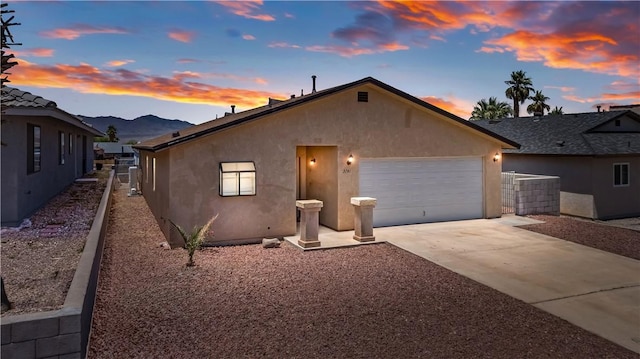 3741 June St, Bullhead City, AZ 86442 - view of front of house with stucco siding, an attached garage, concrete driveway, and a mountain view