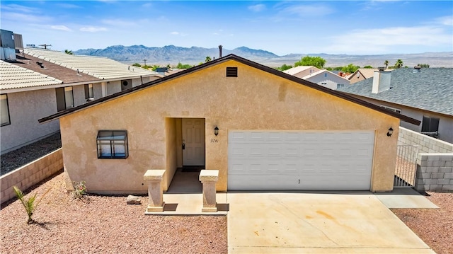 3741 June St, Bullhead City, AZ 86442 - view of front of house with stucco siding, a mountain view, an attached garage, driveway, and fence