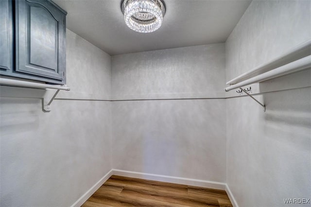 spacious closet featuring a notable chandelier and wood finished floors