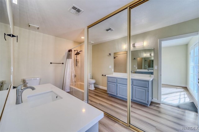 full bathroom with shower / bath combo, visible vents, wood finished floors, and vanity