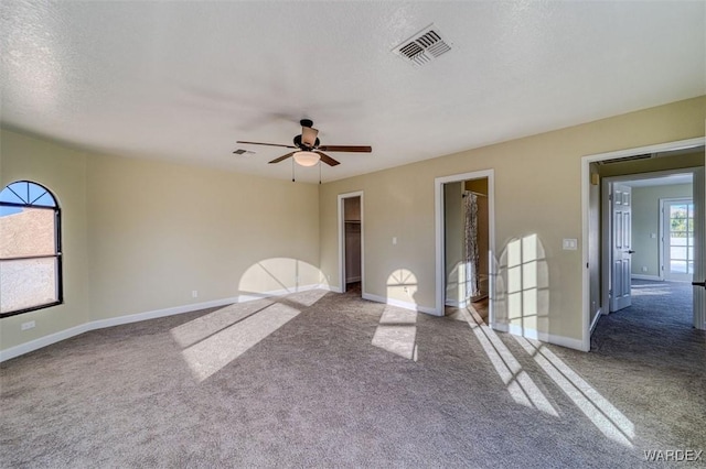 empty room featuring carpet floors, baseboards, visible vents, and a textured ceiling