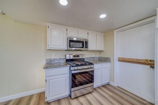 kitchen with light stone countertops, appliances with stainless steel finishes, and white cabinets