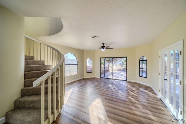 interior space with french doors, visible vents, a textured ceiling, wood finished floors, and stairs