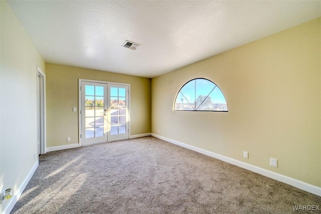 spare room featuring baseboards, visible vents, a textured ceiling, french doors, and carpet floors