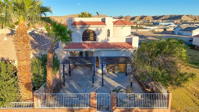 exterior space with a fenced front yard, a tile roof, a mountain view, and stucco siding