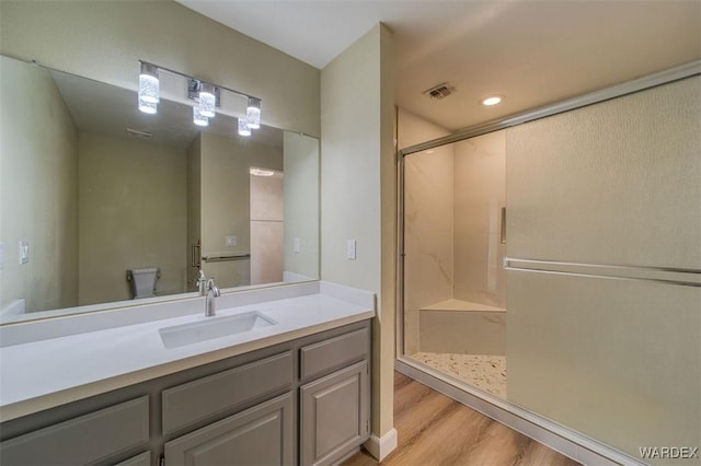 full bath with toilet, wood finished floors, vanity, visible vents, and a stall shower