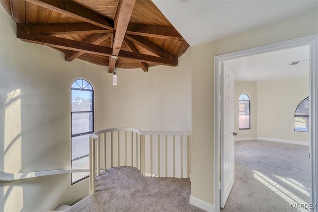 interior space with lofted ceiling with beams, wood ceiling, and light colored carpet