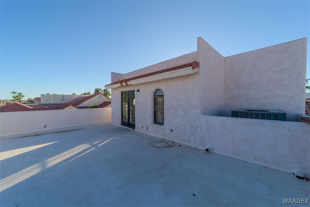 view of side of home featuring a patio, cooling unit, fence private yard, and stucco siding