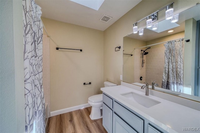 bathroom with baseboards, visible vents, toilet, wood finished floors, and vanity