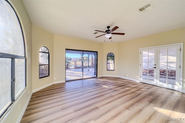 unfurnished room with light wood-style floors, french doors, visible vents, and baseboards