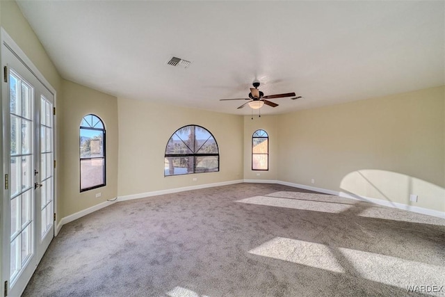 empty room with carpet floors, baseboards, visible vents, and ceiling fan