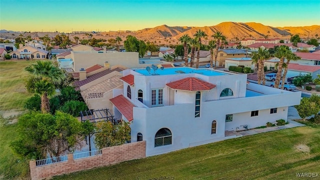 aerial view at dusk featuring a mountain view and a residential view