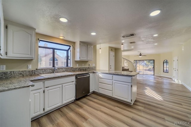 kitchen featuring a peninsula, a sink, visible vents, white cabinets, and dishwasher