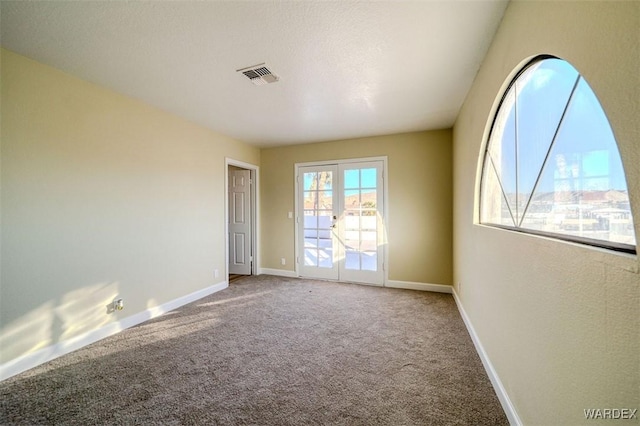 unfurnished room with french doors, carpet, visible vents, and baseboards