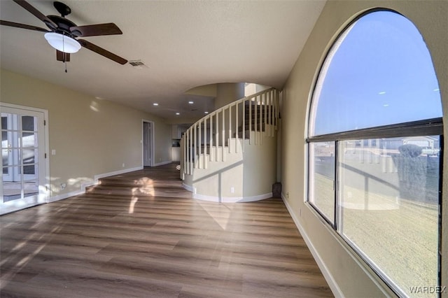 interior space featuring baseboards, visible vents, ceiling fan, dark wood-style flooring, and stairs