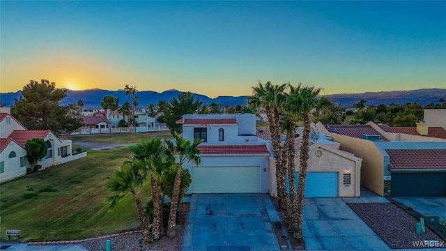 mediterranean / spanish-style home featuring stucco siding, a mountain view, a garage, a residential view, and driveway