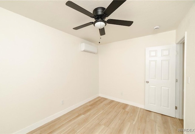 unfurnished room featuring light wood-style floors, a wall unit AC, and baseboards