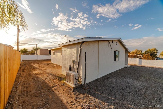 view of side of home with ac unit, a fenced backyard, and stucco siding