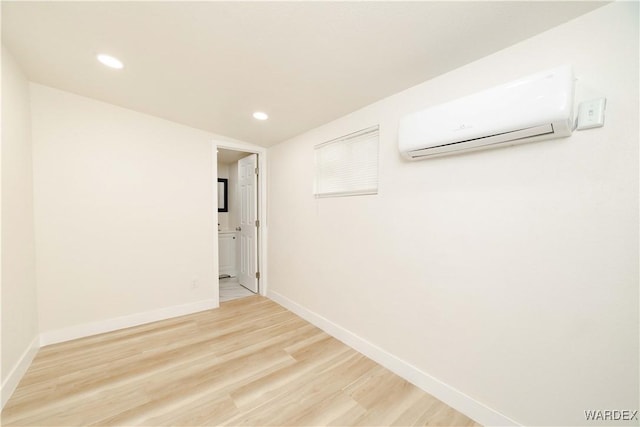 empty room featuring recessed lighting, a wall unit AC, wood finished floors, and baseboards