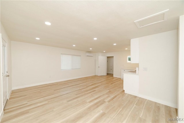 empty room featuring recessed lighting, baseboards, light wood finished floors, and a wall mounted AC