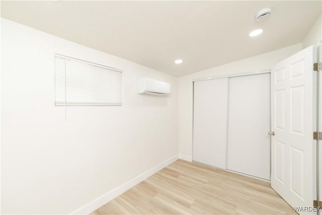 interior space with light wood-style floors, baseboards, an AC wall unit, and recessed lighting