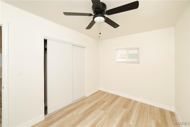 unfurnished bedroom featuring light wood-style floors, ceiling fan, baseboards, and a closet