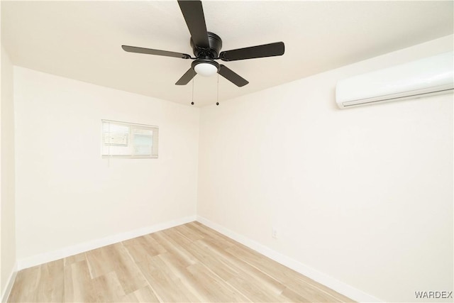 unfurnished room featuring a wall unit AC, baseboards, and wood finished floors