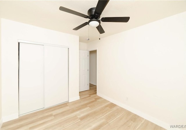 unfurnished bedroom featuring ceiling fan, light wood finished floors, a closet, and baseboards