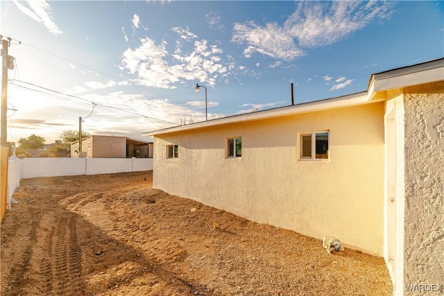 view of side of home with fence and stucco siding