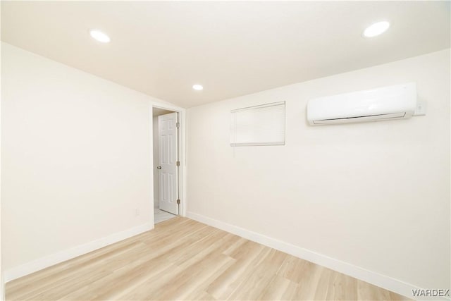 unfurnished room featuring recessed lighting, a wall mounted air conditioner, light wood-style flooring, and baseboards