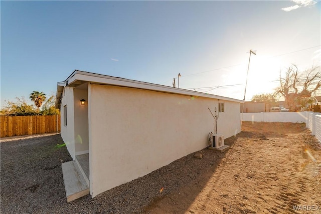 view of side of home featuring a fenced backyard and stucco siding