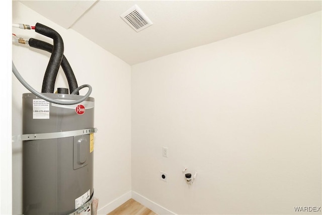 laundry room with visible vents, water heater, light wood-style flooring, electric dryer hookup, and baseboards