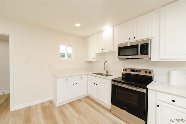 kitchen featuring white cabinets, appliances with stainless steel finishes, light countertops, and a sink