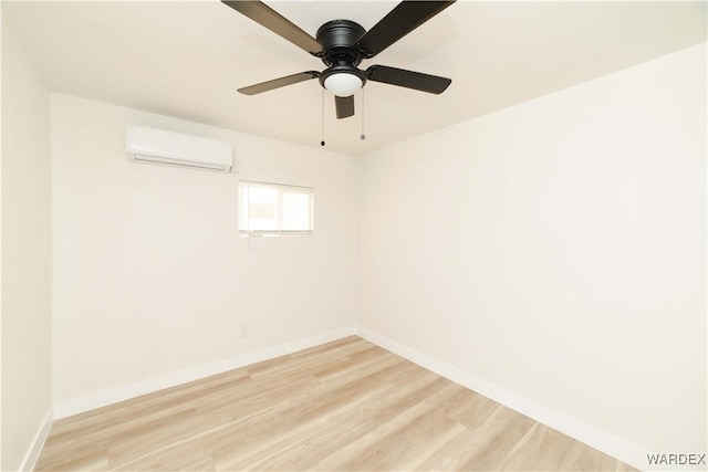 unfurnished room with a wall mounted air conditioner, light wood-style flooring, and baseboards