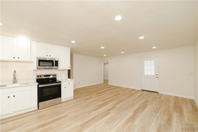 kitchen featuring appliances with stainless steel finishes, white cabinets, light countertops, and a sink