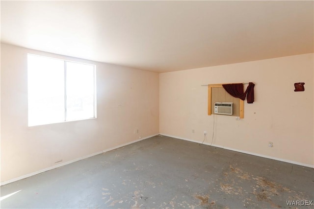 spare room with concrete flooring, an AC wall unit, and baseboards