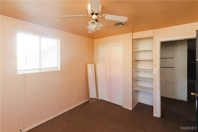 unfurnished bedroom with a ceiling fan, visible vents, and dark carpet