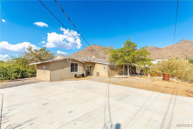 rear view of property with a mountain view, concrete driveway, and a patio