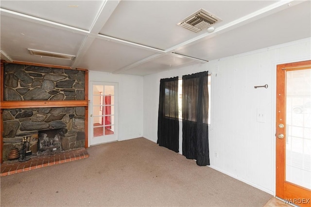 living room with a stone fireplace, carpet, and visible vents