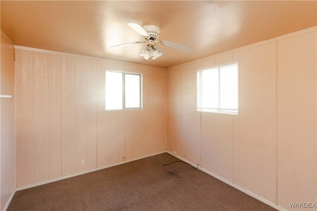 unfurnished room with ceiling fan and dark carpet