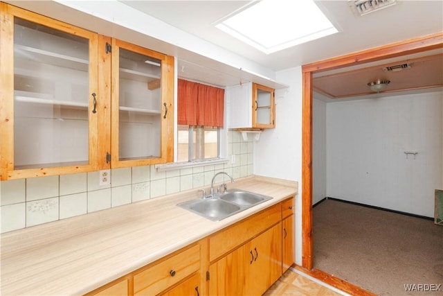 kitchen featuring light countertops, backsplash, a sink, and visible vents