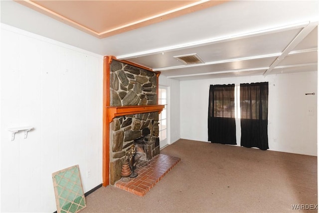 living room with carpet floors, visible vents, and a stone fireplace