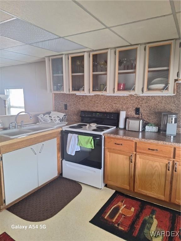 kitchen featuring a paneled ceiling, a sink, electric stove, decorative backsplash, and glass insert cabinets