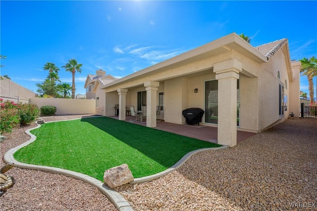 rear view of house with a tiled roof, a patio area, a fenced backyard, and stucco siding