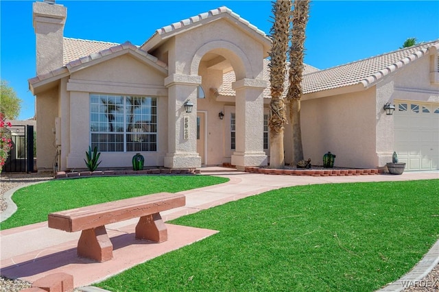 mediterranean / spanish home featuring an attached garage, a front yard, a chimney, and stucco siding