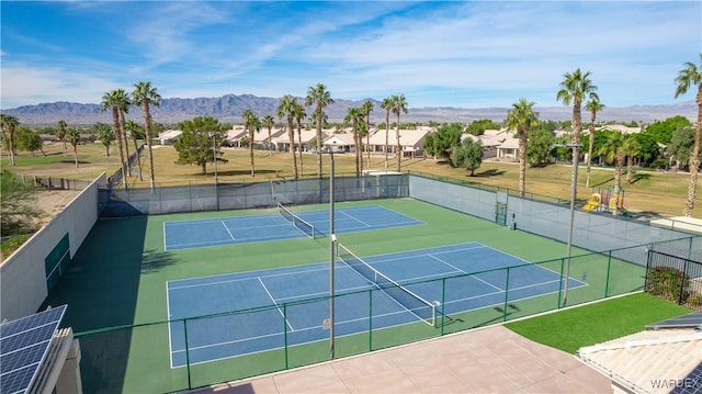 view of sport court featuring a residential view, fence, and a mountain view