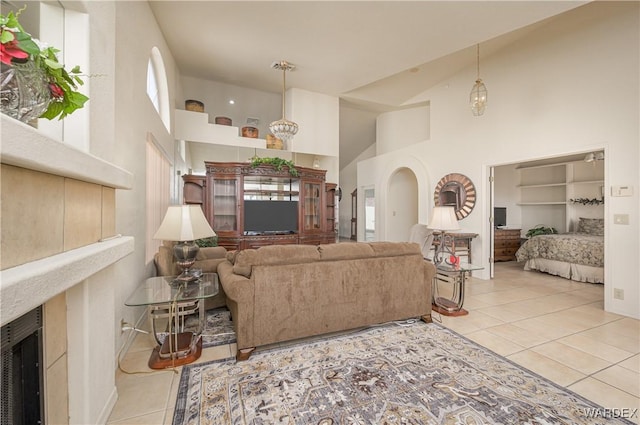 tiled living area with high vaulted ceiling, arched walkways, and a high end fireplace