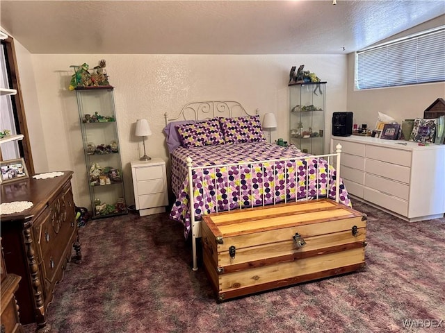 bedroom featuring a textured wall and dark carpet