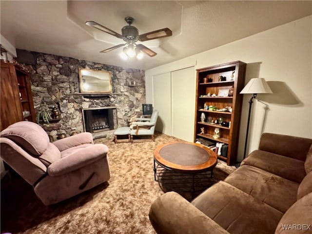 living area featuring ceiling fan and a stone fireplace