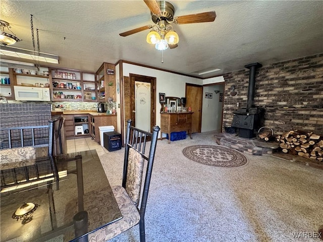 interior space with a dry bar, a wood stove, ceiling fan, a textured ceiling, and brick wall